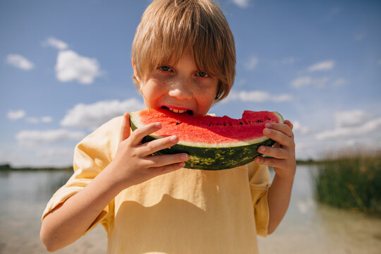 Happy young boy eating a juicy watermelon slice outdoors