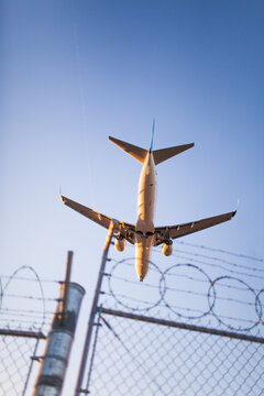 Low angle view of airplane landing over a security fence