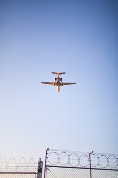 Airplane flying over security fence with barbed wire