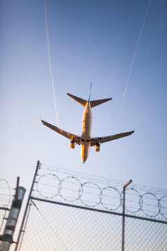 Low angle view of passenger jet flying over security fence