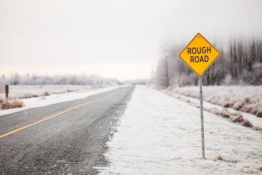 Rough Road warning sign on an empty rural winter road
