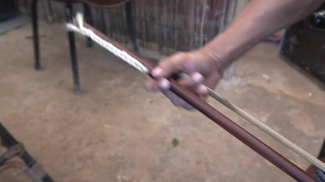 Static 4K close-up with live audio of musician hand bowing strings of traditional Khmer fiddle Tro Sor in music cafe in Siem Reap, Cambodia