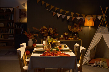 Festive dining table arranged with autumn dinnerware, candles and floral decor for Thanksgiving celebration. Useful for holiday party promotions and catering advertisements © pressmaster