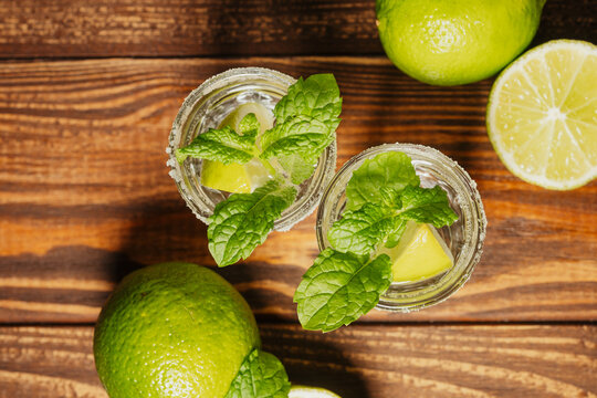 Refreshing drinks with lime and mint on a wooden table