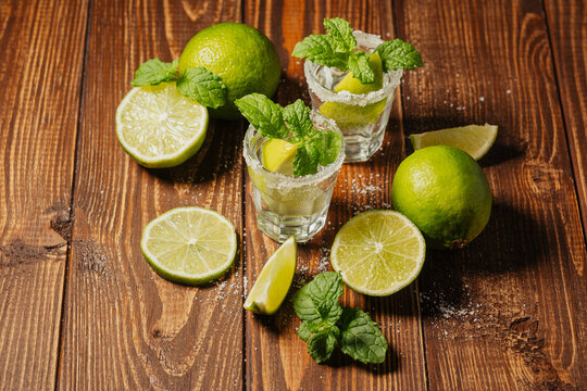 Tequila cocktail with fresh mint and lime on wooden background