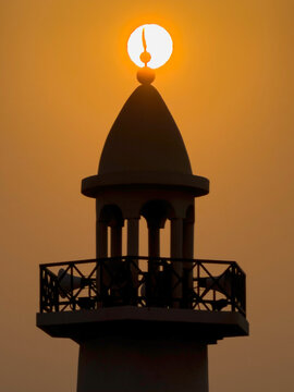 Doha, Qatar - August 10, 2026: Silhouette of Minarte aligned with the glowing sunset sun, dramatic golden sky sunset view. wakrah Qatar