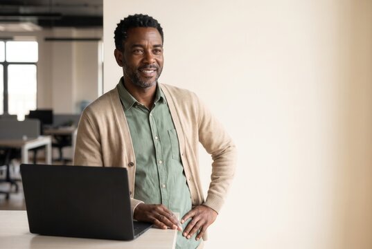 Confident adult learner standing beside a laptop