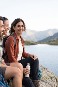 Friends resting beside a mountain lake after a hike