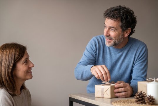 Man opening a small gift while his partner watches