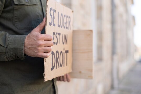 Hands holding a French sign asserting the right to housing