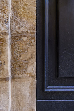 Chiseled Rough Limestone Wall Moulding Contrasting with Clean Lines of Dark Painted Wooden Door Frame