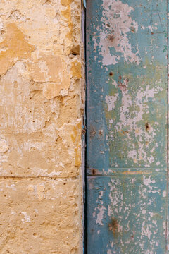 Contrast Between Textured Eroded Sandstone Wall and Weathered Peeling Turquoise Green Painted Wooden Door