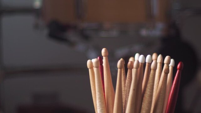 Hands with painted nails display bundles of wooden incense sticks in a room