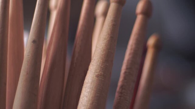 Wooden and painted drumsticks stand upright together in a music shop display