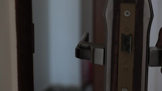 Extreme close-up of an anxious man opening and closing a door, hesitating to leave home and struggling to go outside, depicting social anxiety, avoidance, fear, uncertainty and emotional distress