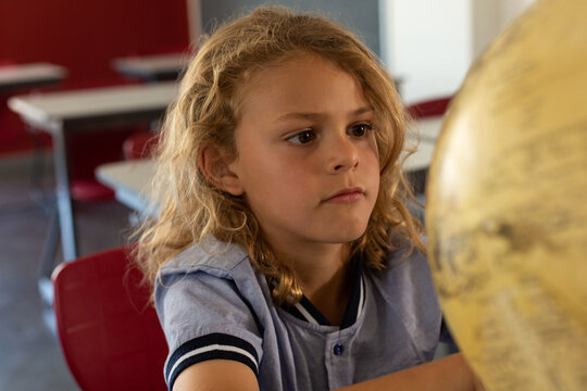 Schoolgirl studying globe at desk in a classroom