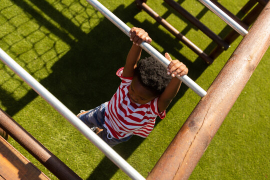 Schoolboy playing on horizontal ladder in the school playground