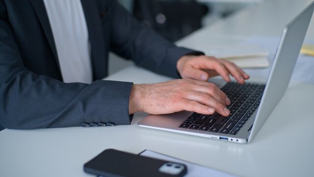 Close up male hands typing laptop chatting with e-mails in company at table unknown Caucasian business man working with computer web chat with client distant trading online job businessman in office