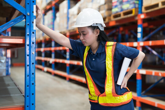 Warehouse worker, warehouse storage and logistics. Asian warehouse female worker have accident, backache while working in storage warehouse