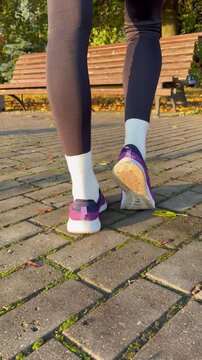 Close-up rear view of a woman doing calf raises and stretching in an autumn park. Fitness, sports, warm-up routines, and healthy lifestyle concepts