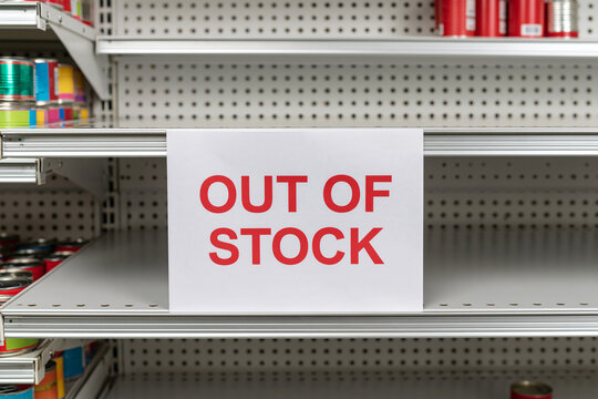 An out of stock sign on empty supermarket shelves with bright lighting. Perfect for retail supply chain crisis concepts.