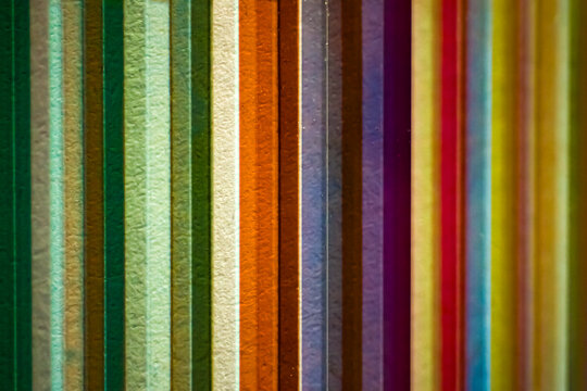 Abstract background of colorful vertical stripes in green, yellow, orange, purple and turquoise, with translucent textures and contrasting light and shadow