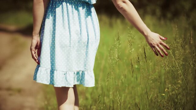 Woman Walking Along Country Path Touching Tall Grass With Hand While Enjoying 