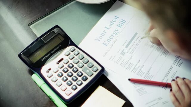 Accountant Calculating Energy Bill With Calculator And Pen. Managing Budget And Financial Paperwork