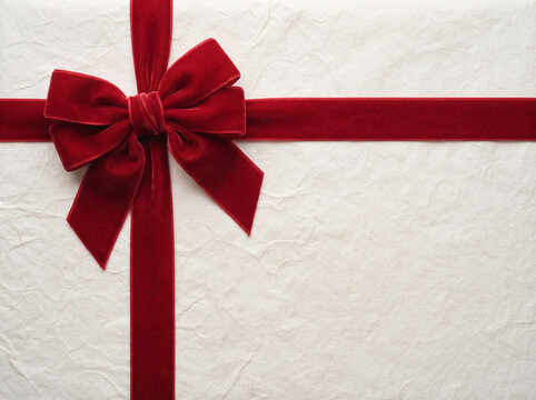 Close up top view of luxury red velvet ribbon bow on white gift wrapping paper