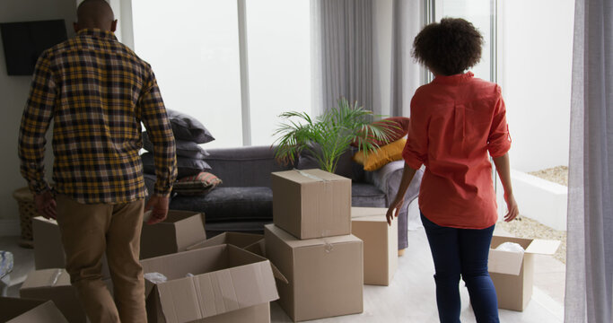 African american couple unpacking boxes on floor at home