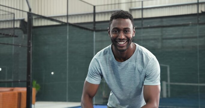 African American man in sportswear entering court, flipping paddle, tapping net readying to play