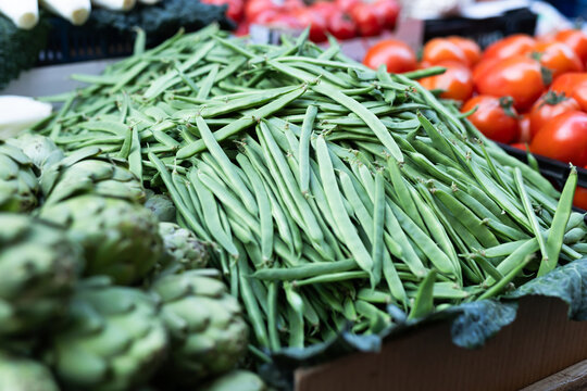 Box is filled with green beans, grocery store display case.