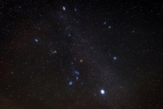 A dense field of stars fills the dark night sky with prominent bright stars visible against the Milky Way. Deep space and subtle celestial colors create a dramatic astronomical background