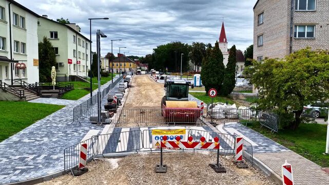 Road construction site with a roller machine compacting gravel for a new pedestrian crossing