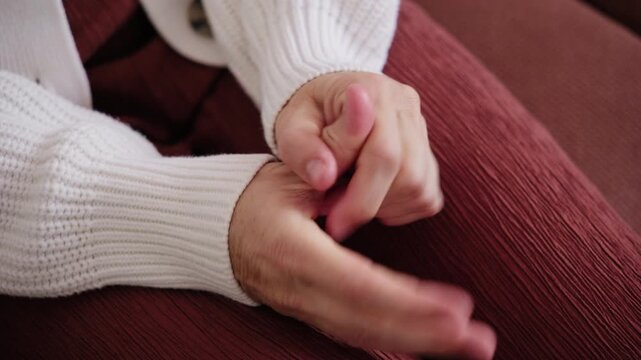 Close-up of a woman nervously rubbing and fidgeting with her hands while sitting on a couch, expressing anxiety, stress, and emotional tension.