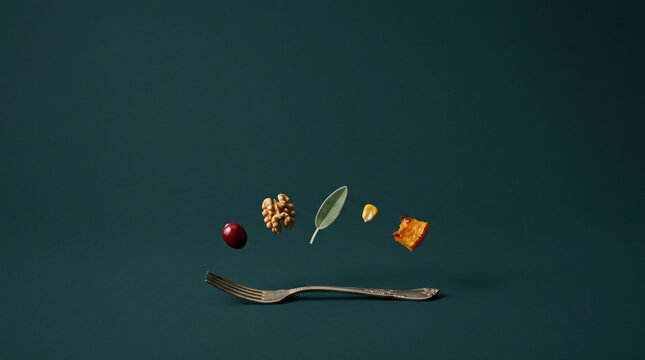 Food ingredients levitating over a silver fork on a dark background. Minimalist Thanksgiving concept.