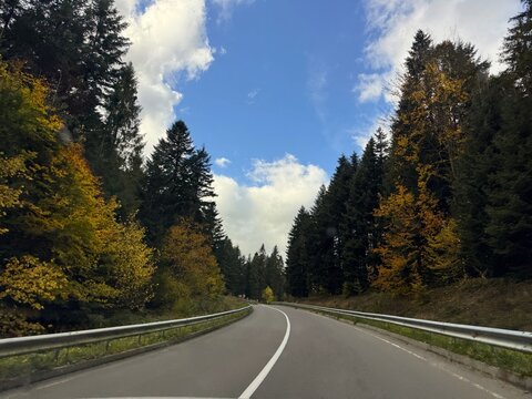 A vibrant autumn mountain landscape. Fall colors stretch across the slopes along a quiet mountain road.