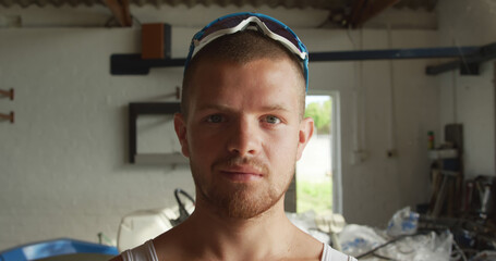 Portrait of serious caucasian male rower with sunglasses on head in boathouse on sunny day © WavebreakMediaMicro