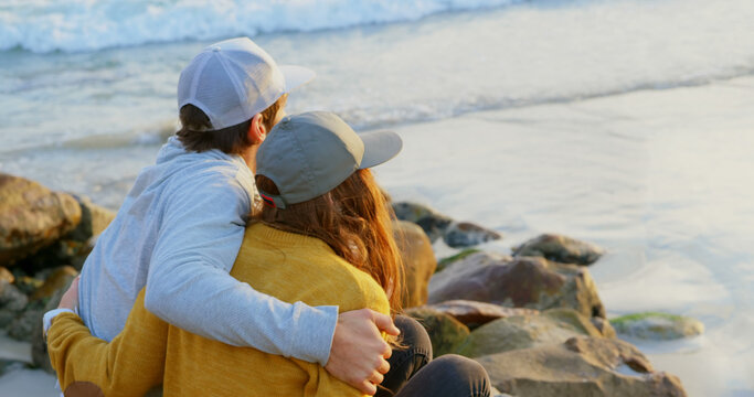 A young couple shares a peaceful embrace by the sea, embodying leisure and connection.
