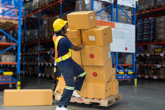 Warehouse worker accident at work. Warehouse worker falling down on concrete floor after cardboard boxes collapsed fell from wooden pallet cart, occupational workplace safety accident concept