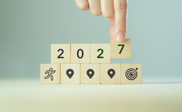 2027 Goal Setting Concept. Business Planning, Milestones, Target Achievement and Future Success. Placing a wooden 2027 block above milestone and target icons. New year goal setting and future success.