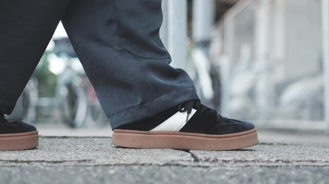 Close Up of Black Sneakers Walking on Asphalt Sidewalk in Slow Motion