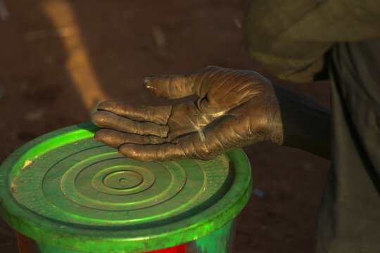 Close up of an outstretched hand of a beggar resting on a green bucket lid, Mopti Region, Mopti, Mali