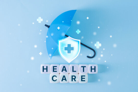 Healthcare word dice with blue umbrella and medical shield icon on light background. Health insurance, medical protection or wellness coverage concept.