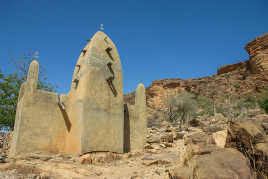 Mud mosque with pointed minarets and wooden beams below the cliff, Mopti Region, Bandiagara, Mali