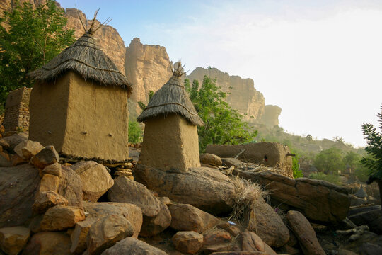 Two thatched mud granaries on boulders with hazy cliffs in the background, Mopti Region, Bandiagara, Mali