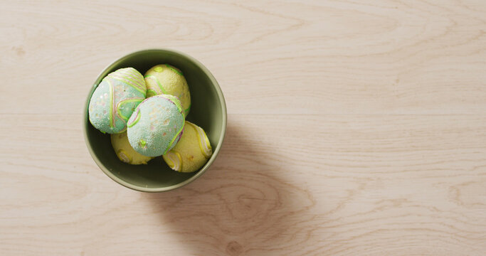 Image of decorated colorful easter eggs in bowl on a wooden surface