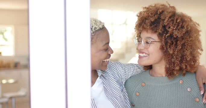 Happy diverse lesbian couple embracing and looking at each other at home