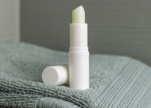 Open lip balm stick with a lid mockup on green bath towel. Herbal cosmetic product for home use