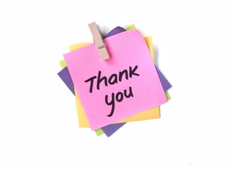 Colorful adhesive notes with thank you handwriting clipped using wooden peg on white background. Ideal for gratitude, business, appreciation, and greeting message concept © Eka